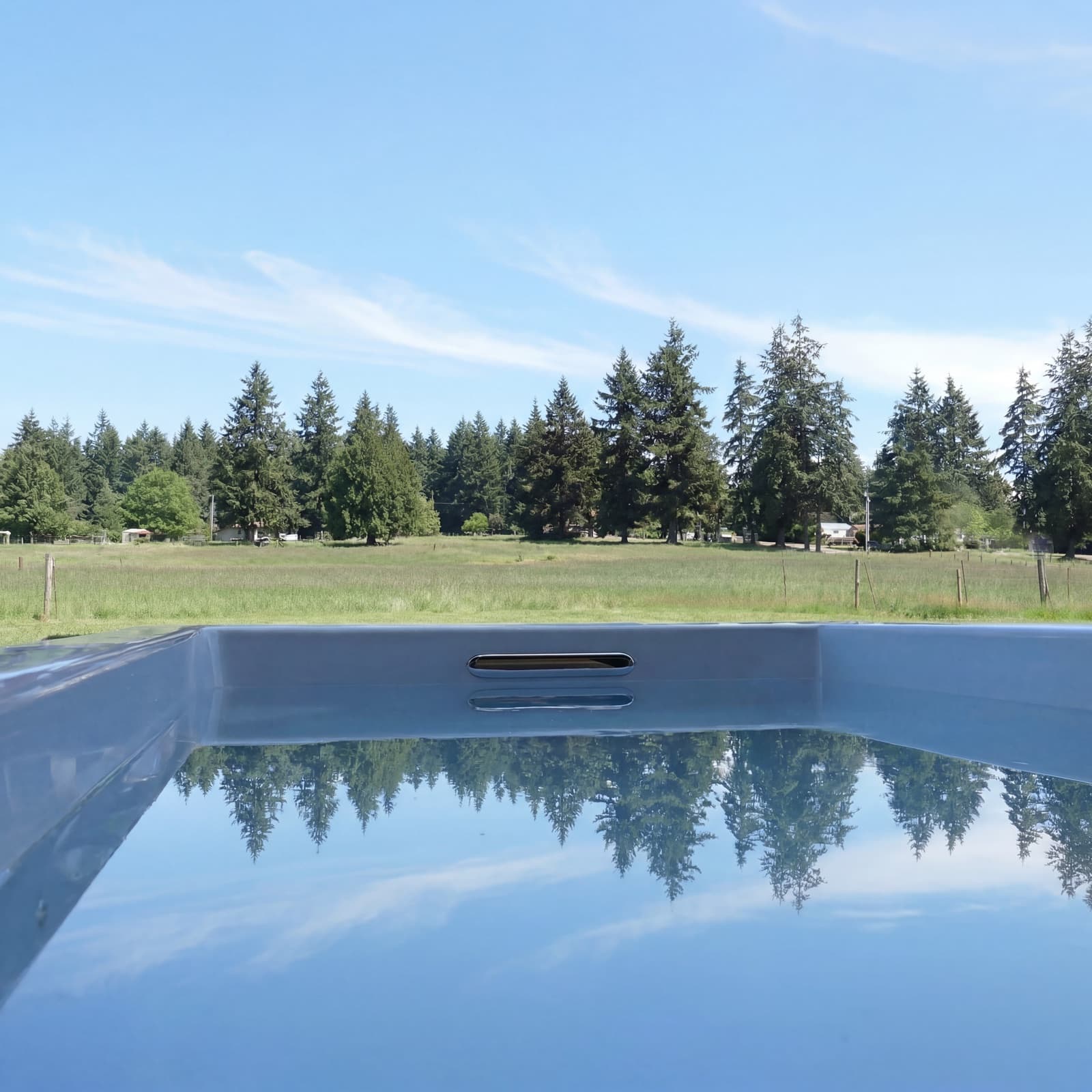 Still plunge water filled to the brim, the Graham, Washington treeline and sky mirrored on the surface